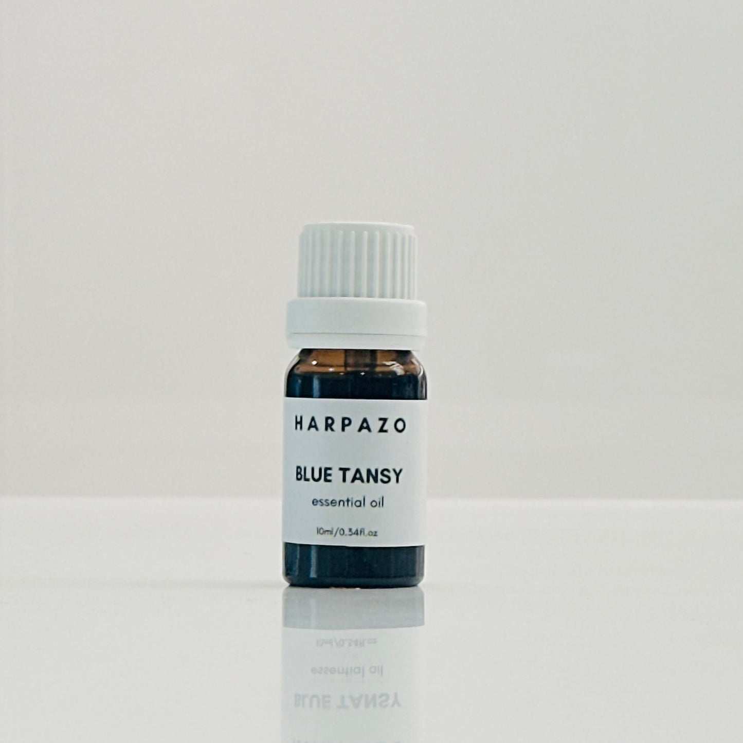 A small bottle labeled 'HARPAZO BLUE TANSY essential oil' with a capacity of 10ml, containing blue tansy oil.