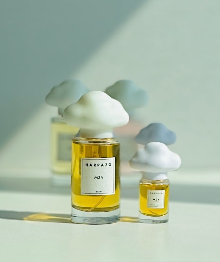 Two perfume bottles with cloud-shaped caps on a light background