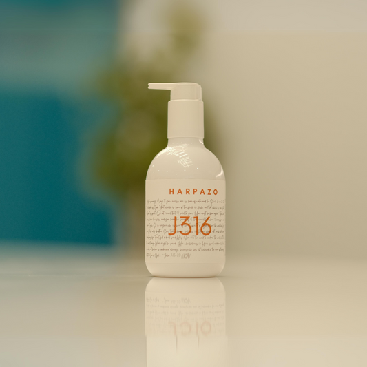 A pump bottle of J316 hand wash with white and orange label on a light background.