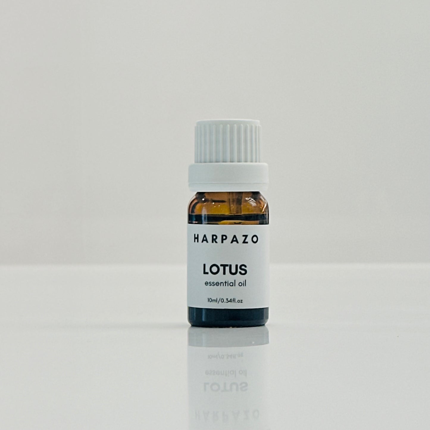 A small bottle labeled LOTUS essential oil on a light background.