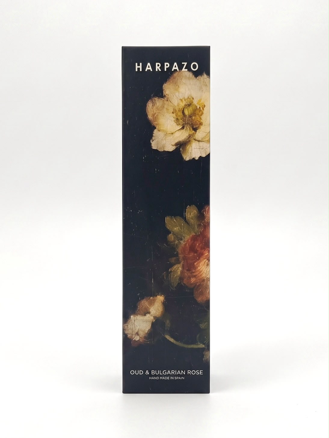 A tall, narrow rectangular product box for Harpazo Oud & Bulgarian Rose, featuring a dark background with classical oil-paint style floral illustrations in cream, red, and green, set against a clean white studio background.