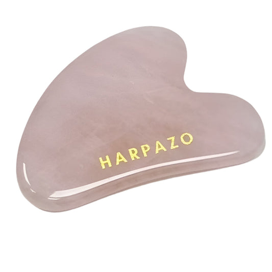 Pink gua sha tool with 'Harpazo' branding on a white background