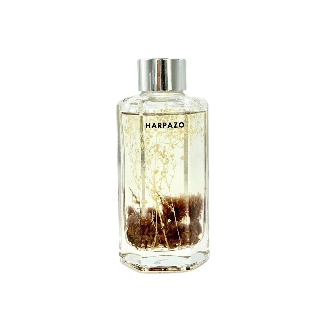 A clear glass reed diffuser bottle with a silver cap and visible fragrance oil and reeds inside.