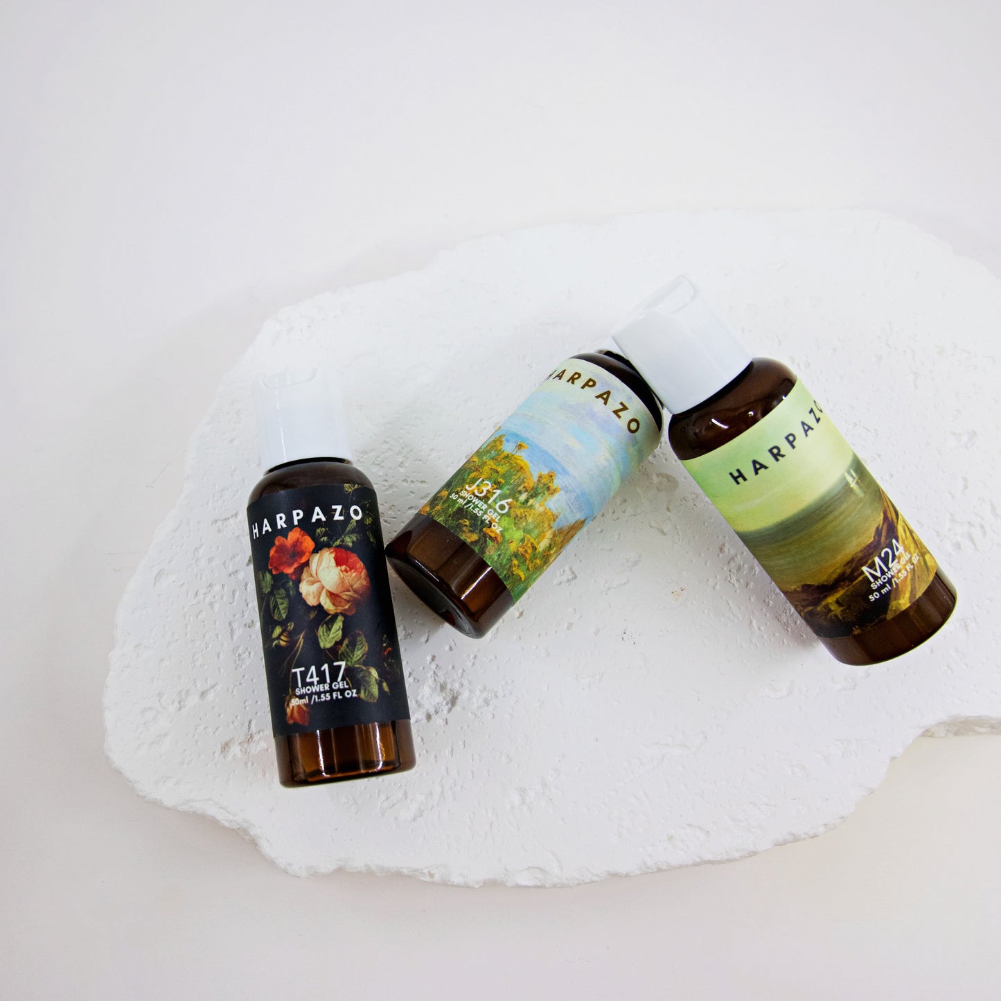 Three bottles of Harpazo products on a white stone surface
