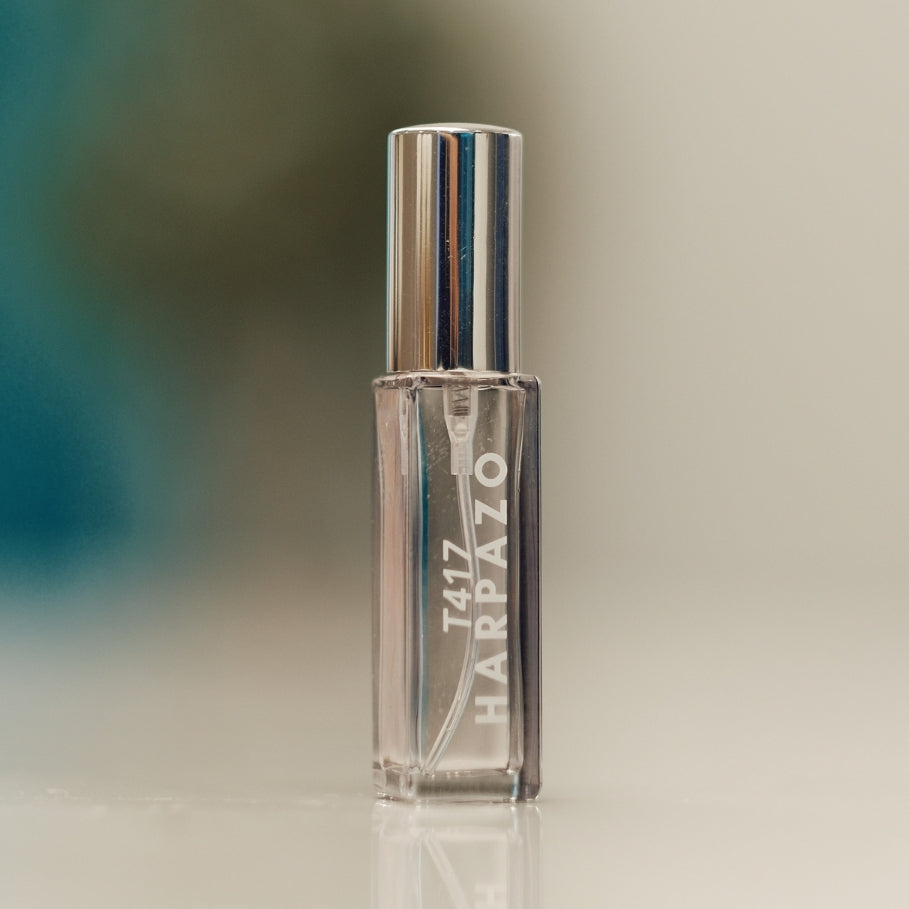 A clear glass perfume bottle with a silver cap, labeled T417