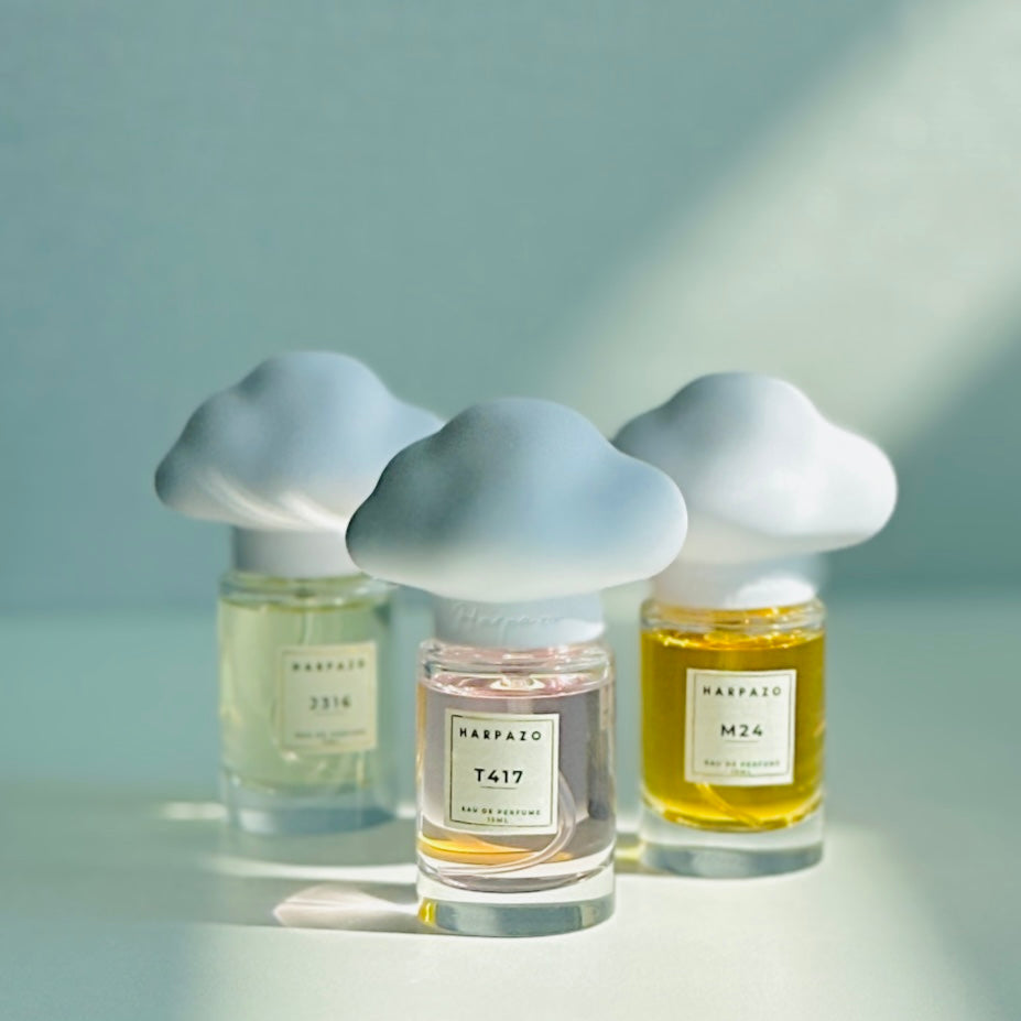 Three glass bottles of perfume with unique cloud-shaped caps, labeled M24, J316, and T417, on a light background.