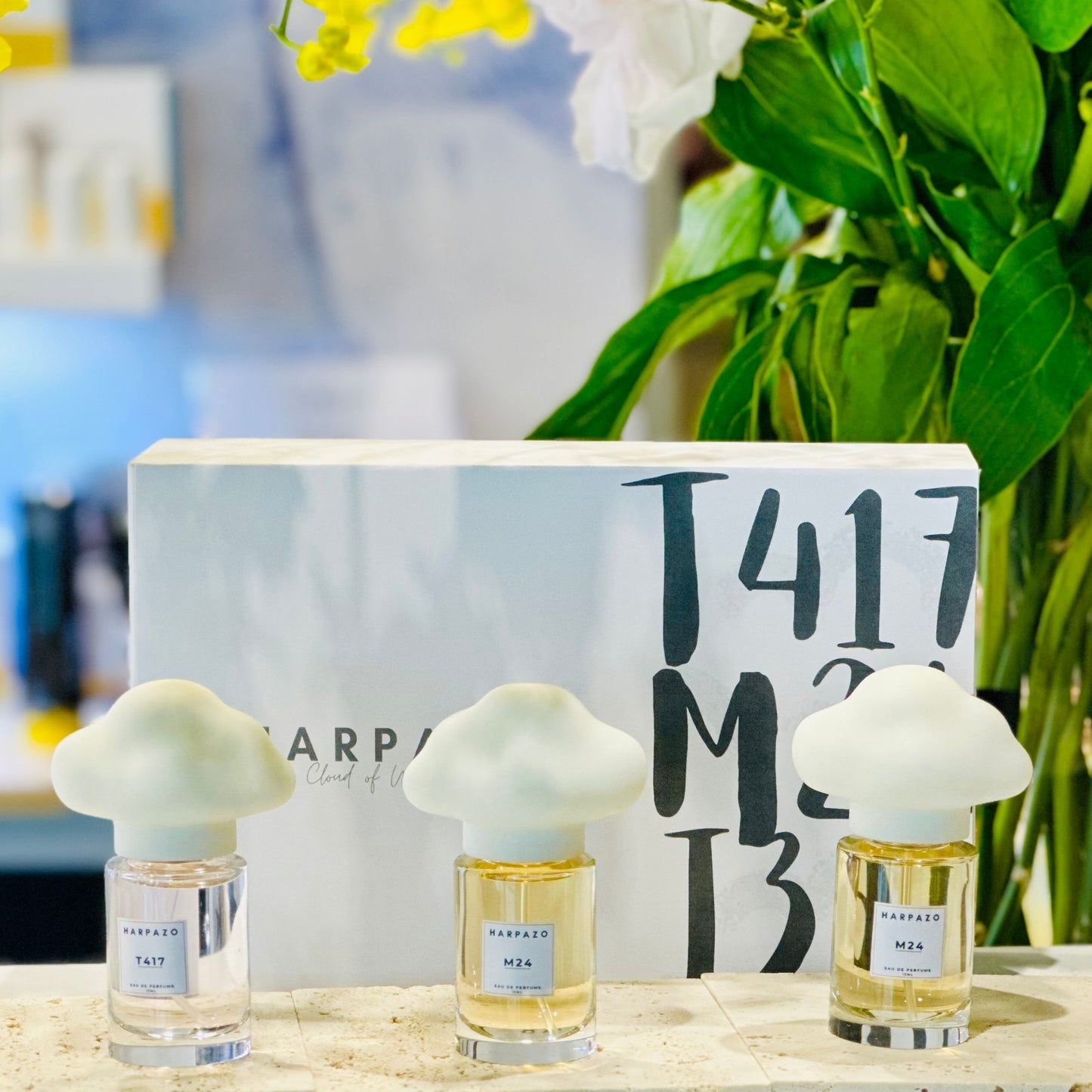 Three glass bottles of perfume with unique cloud-shaped caps, labeled M24, J316, and T417, on a light background.