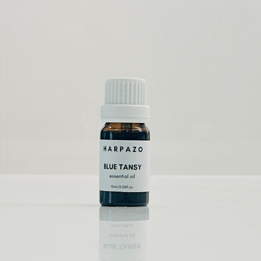 A small bottle labeled 'HARPAZO BLUE TANSY essential oil' with a capacity of 10ml, containing blue tansy oil.
