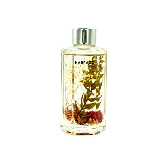 A clear glass reed diffuser bottle with a silver cap, filled with a yellowish liquid and adorned with what appears to be plant elements, possibly oak and red currant as mentioned in the product description.