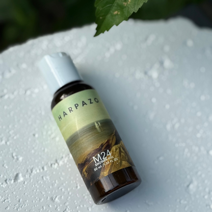 Harpazo M24 shower gel bottle on a textured white surface with a leaf in the background