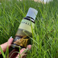 Hand holding a bottle labeled 'Harpazo' in grass