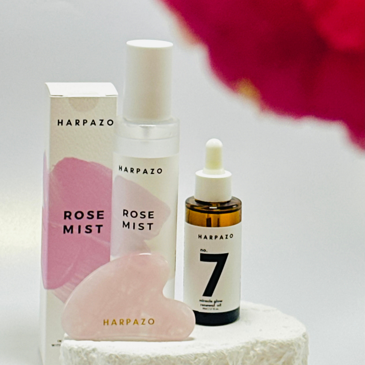 Harpazo skincare products including a box, bottle, and dropper on a white surface with a pink flower in the background.