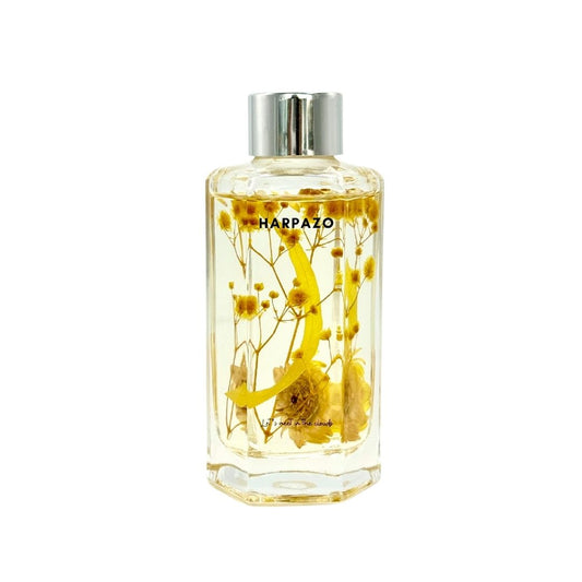 A clear glass reed diffuser bottle with yellow and orange flowers inside, labeled 'HARPAZO'.