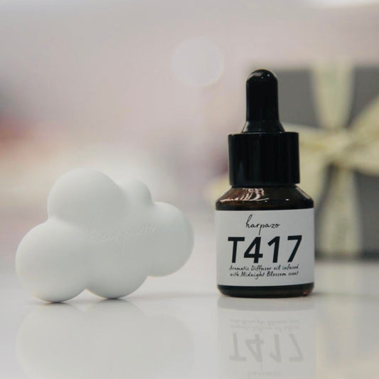 A bottle of T417 aromatic diffuser oil with a dropper, accompanied by a white diffusing cloud, all presented on a white surface with a blurred light in the background.