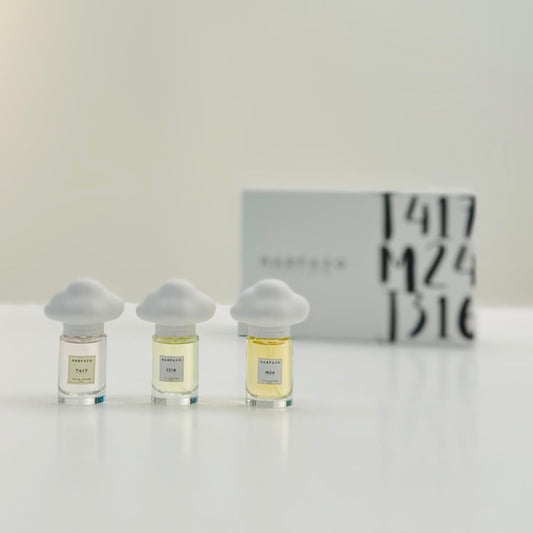 Three glass bottles of perfume with unique cloud-shaped caps, labeled M24, J316, and T417, on a light background.
