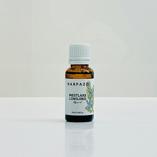 A bottle of 'Harpazo West Lake Longjing' diffuser oil, with a white cap and a label featuring green text and a graphic of a tea plant.